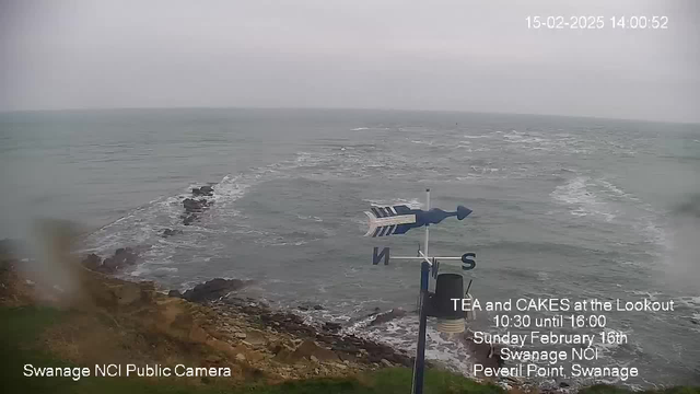 A coastal scene showing a cloudy sky over the sea. The water appears to be choppy with gentle waves, and rocky formations are visible near the shore. In the foreground, there is a weather vane with directions indicated, pointing towards the south. Text in the image advertises a tea and cake event at a lookout point, including details about the date and time. The scene captures a tranquil yet dynamic coastal environment.