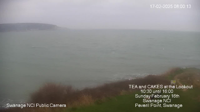 A cloudy view of the ocean with choppy waters, extending to a rocky coastline in the distance. The foreground features a grassy area with some sparse vegetation. Text at the bottom indicates an event called "TEA and CAKES at the Lookout," scheduled for February 16th at Swanage NCI, Peveril Point, with times specified from 10:30 to 16:00. The date and time displayed in the corner shows "17-02-2025 08:00:13."