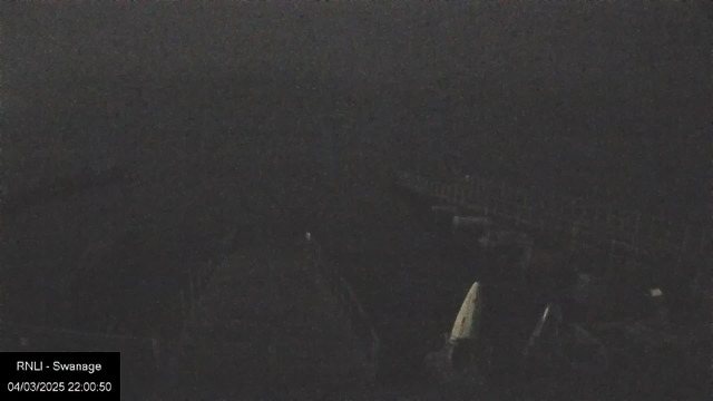 A dark and dimly lit scene featuring shadows of structures, possibly a pier or walkway, and indistinct shapes in the distance. The image appears grainy, with low visibility. A timestamp in the bottom left corner indicates the image was taken on April 3, 2025, at 22:00:50.