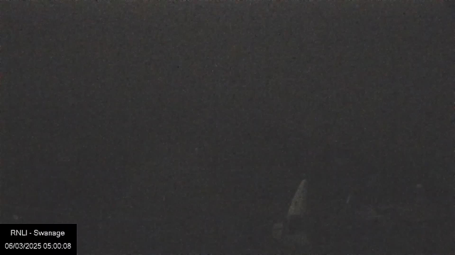 A very dark image with limited visibility. The scene appears to be mostly black with slight variations in shade. There is a faint outline on the right side, possibly indicating a structure or object, but details are indistinct. The timestamp at the bottom shows "06/03/2025 05:00:08," and a label "RNLI - Swanage" is present in the lower left corner.