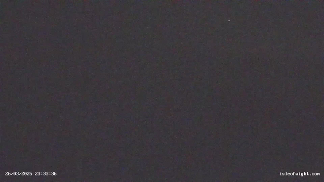 A dark image with minimal visibility. In the top right corner, a small bright point likely represents a distant star. The bottom left displays a timestamp reading "26/03/2025 23:33:36" along with a web address at the bottom right. The overall scene is predominantly black with very little detail visible.