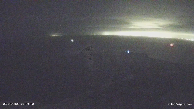 A dimly lit scene of the ocean at night, with some distant lights visible along the horizon. The sky appears cloudy and dark. There are faint reflections on the water, indicating waves or ripples. Time stamp at the bottom indicates the image was captured on March 29, 2025, at 20:59:52.