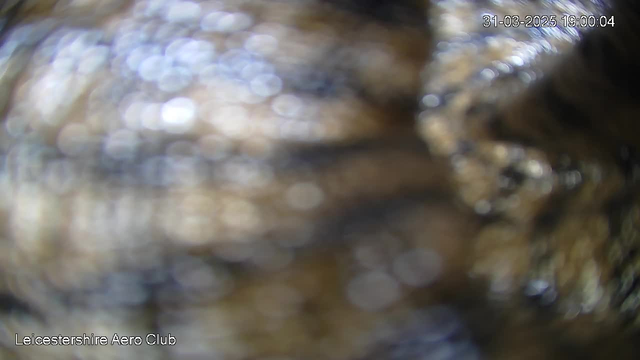 The image shows a blurred and out-of-focus view, consisting of soft textures and bokeh effects with varying shades of blue and brown. The date and time in the corner indicate March 31, 2025, at 19:00:04. The bottom left corner displays the text "Leicestershire Aero Club." Overall, the image lacks clear details and appears hazy.