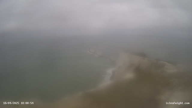 A blurry view of a cloudy sky and a turbulent sea. The shoreline is faintly visible, with a hint of land jutting into the ocean. The scene appears grey and foggy, suggesting overcast weather. The date and time are displayed in the bottom left corner, indicating it is 18:00 on April 18, 2025.