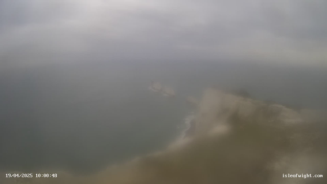 A cloudy sky is overhead, with varying shades of gray dominating the scene. Below, a murky ocean can be seen, blending into the horizon where it meets the sky. In the distance, shadows of rocks or land formations break the surface of the water, while the foreground is mostly obscured by a haze. Time and date are displayed at the bottom left corner, indicating April 19, 2025, at 10:00:48.