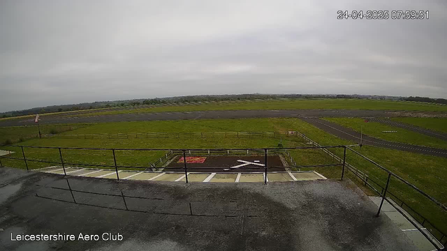 An overcast scene showing a paved approach and a grass runway at Leicestershire Aero Club, with a small helipad marked with an "H" near the bottom center. The airport is surrounded by open fields and distant hills, under a cloudy sky. The timestamp in the top right corner indicates the date and time as April 24, 2025, 07:59:51.