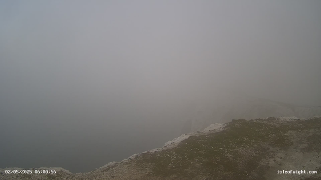 A foggy landscape with only a small patch of rocky ground visible at the bottom right corner. The rest of the scene is enveloped in dense fog, obscuring any other details.