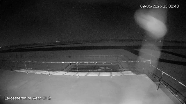 A black-and-white nighttime image from a webcam shows an airfield with fencing and runway markings. The sky is dark, and there are no visible aircraft or people. The date and time in the top right corner reads "09-05-2025 23:00:40," and "Leicestershire Aero Club" is noted in the bottom left corner.