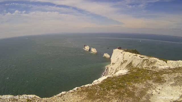 A panoramic view from a webcam showing white chalk cliffs overlooking the sea, with a lighthouse on one of the cliffs. In the distance, there are rock formations protruding from the water, and several boats sailing in the ocean. The sky is partly cloudy with patches of blue. The timestamp in the corner indicates the date and time: May 20, 2023, at 1:01 PM.