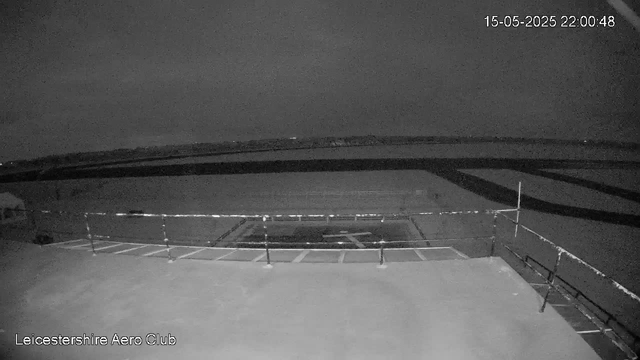 A black-and-white webcam image of an empty rooftop terrace with a metal railing, likely taken at night. The horizon shows a dark sky with no visible stars, and the image is timestamped "15-05-2025 22:00:48" in the top right corner. The bottom left corner indicates it is from the "Leicestershire Aero Club."