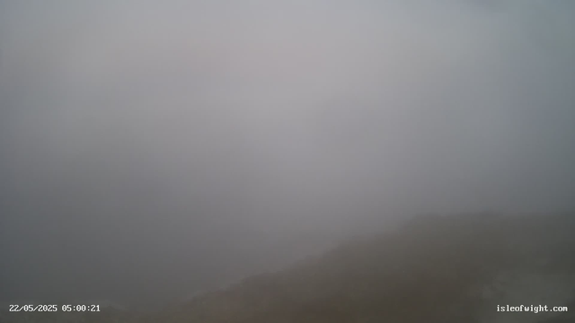 A foggy scene with limited visibility, where the coastline is faintly visible in the lower right corner. There is a timestamp in the lower left corner showing "22/05/2025 05:00:21" and a website URL "isleofwight.com" in the lower right corner.