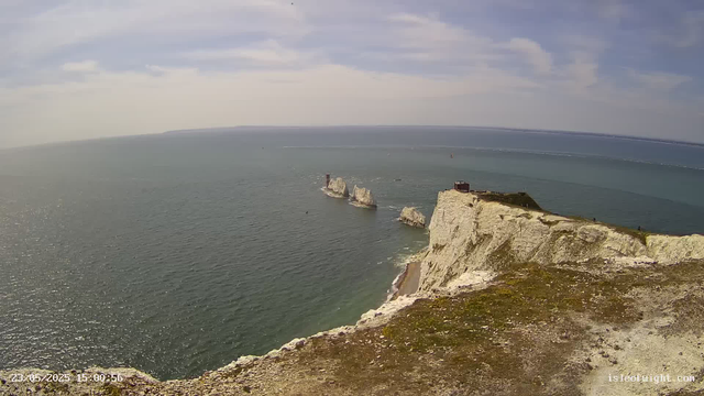 A panoramic view of white chalk cliffs and the ocean, taken from a webcam. The cliffs extend along the coastline with a grassy area at the top, and there are some small structures visible. The sea below is calm, with ships in the distance, and the sky has scattered clouds. The timestamp in the bottom left indicates the date and time as 23/05/2023 at 15:00:36.