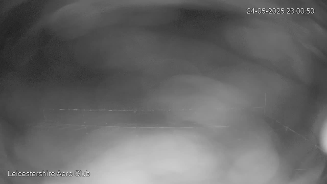 A black and white webcam image with a timestamp of "24-05-2025 23:00:50" in the top right corner. The image shows a blurry, dark indoor space with some faint horizontal lines. In the bottom left corner, there is text that reads "Leicestershire Aero Club."