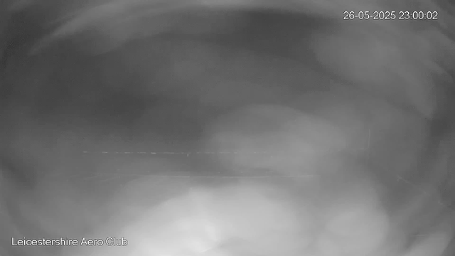 A black and white webcam image showing a mostly dark scene with faint, blurry lines across the middle. The top right corner displays a timestamp: "26-05-2025 23:00:02," and the bottom left corner has the text "Leicestershire Aero Club." The overall image appears unclear and lacks distinguishable objects.