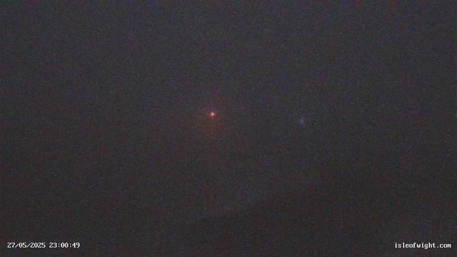 A dark night sky filled with faint stars, with a small bright reddish object near the center and a slightly dimmer blueish object to the right. The bottom left corner displays a timestamp reading "27/05/2025 23:00:49," and the bottom right corner shows the website "isleofwight.com."