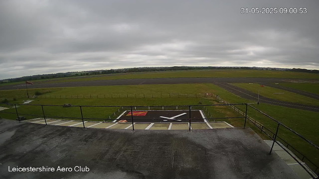 Overcast sky at a small airfield with a runway in the background and a launch pad in the foreground, surrounded by a grassy area and safety barriers. The image is from the Leicesterhire Aero Club, captured on 31st May 2025 at 09:00 AM.