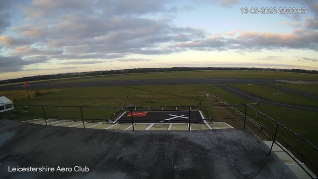 A view from a webcam showing an airfield with a runway in the background and a helipad marked with a large white "H" and red and black markings in the foreground. The sky is partly cloudy with patches of blue, and the time and date in the top right corner indicate it is 8:00 PM on August 16, 2025. The bottom left corner displays the text "Leicestershire Aero Club".