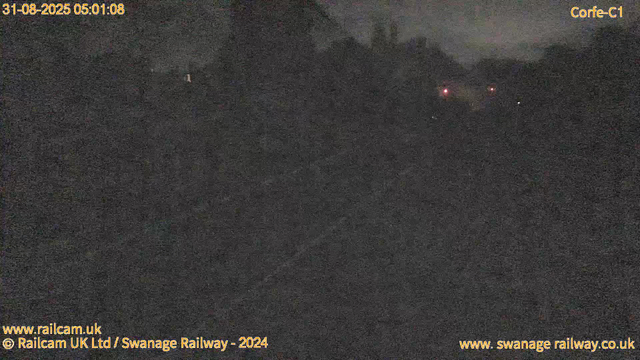 A dark, grainy image captured at night, with very little visible detail. Faint red and white lights are seen in the distance, possibly from a distant vehicle or structure. The timestamp at the top left indicates the date and time as August 31, 2025, at 05:01:08. The image is credited to Railcam UK Ltd / Swanage Railway, 2024.