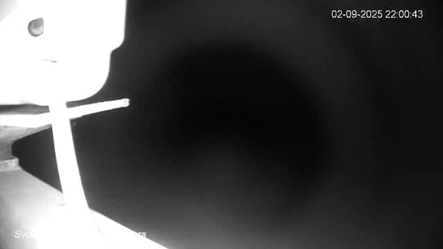 A black tunnel or pipe extends into darkness, with a portion of a white object or surface partially visible on the left side of the image, and a timestamp showing "02-09-2025 22:00:43" in the top right corner. The image appears to be captured from a security or webcam feed.
